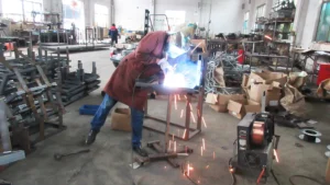 a robotic welding arm at SUN-Carts factory applying precise welds to a chassis frame joint in the main weld zone for electric golf cart production